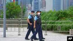 FILE - Police officers patrol outside a train station in Hong Kong, June 30, 2022.