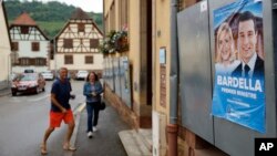 Voters arrive at a polling station in Soultz-Les-Bains, eastern France, June 30, 2024. A poster with French far-right leaders Marine Le Pen and Jordan Bardella is seen on the right.