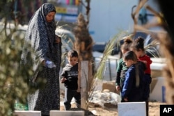 ชาวปาเลสไตน์ไปเยี่ยมสุสานของผู้ที่ถูกสังหารในการทิ้งระเบิดของอิสราเอล และถูกฝังอยู่ภายในพื้นที่โรงพยาบาลชิฟา ของฉนวนกาซ่า เมื่อ 31 ธ.ค. 2566