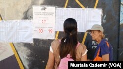 Venezuela'da dün yapılan halk oylamasında seçmenler isimlerini listeden kontrol ediyor
