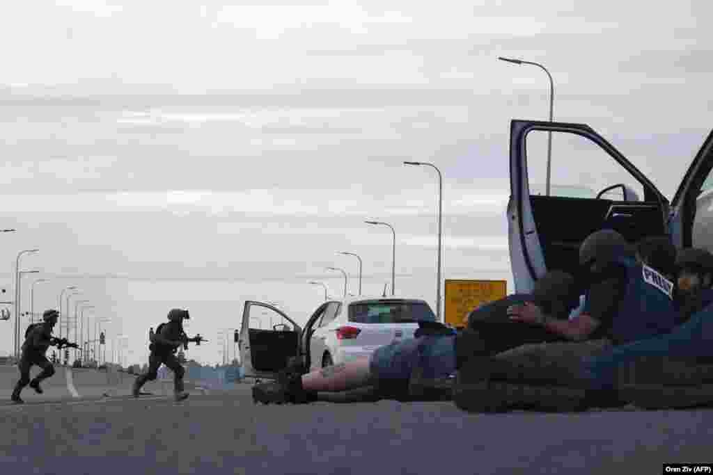 Journalists take cover behind cars as Israeli soldiers take position during clashes with Palestinian fighters near the Gevim Kibbutz, close to the border with Gaza, Oct. 7, 2023.