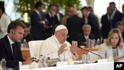 French President Emmanuel Macron, left, and Italy's Prime Minister Giorgia Meloni, right, listen to Pope Francis at the 50th G7 summit at Borgo Egnazia, southern Italy, June 14, 2024.
