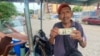 ARCHIVVO - Un vendedor ambulante de golosinas y cigarros muestra un billete de un dólar estadounidense en Maracaibo, Venezuela, en agosto de 2023.