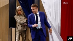 French President Emmanuel Macron and his wife Brigitte Macron leave the voting booth before voting in Le Touquet-Paris-Plage, northern France, June 30, 2024.