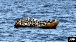 Wahamiaji wenye asili ya Kiafrika wakiwa wamejazana katika boti dogo huku walinzi wa pwani ya Tunisia wakijitayarisha kuwahamisha katika chombo kingine salama, katika eneo la bahari kati ya Tunisia na Italia Aug. 10, 2023. 