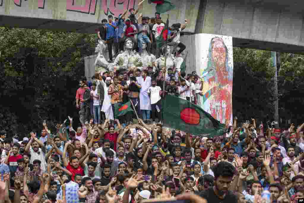 Protesters climb a public monument as they celebrate the news of Prime Minister Sheikh Hasina's resignation, in Dhaka, Aug. 5, 2024.