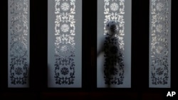 A soldier dressed as an usher stands behind a door on the sideline of the National People's Congress at the Great Hall of the People in Beijing, March 6, 2024.