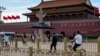 A security person watch over residents passing in front of Tiananmen Gate in Beijing, June 4, 2023.