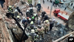 In this photo provided by the Ukrainian Police Press Office, emergency workers search for victims of a Russian rocket attack that damaged a multistory building in central Kharkiv, Oct. 6, 2023.