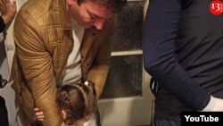 In a screengrab from video, the 3-year-old daughter of Azeri journalist Aziz Orujov hugs her father before he is arrested in November. (Kanal 13 YouTube channel)