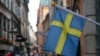 Bendera Swedia berkibar di luar sebuah toko dengan latar belakang kota tua Stockholm, Swedia, 14 Juli 2023. (Foto: REUTERS/Tom Little)