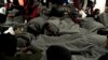 Migrants are wrapped with blankets as they gather on the deck of the Ocean Viking rescue ship, in the Strait of Sicily, in the Mediterranean Sea, Nov. 4, 2022.