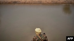 Un soldat malien patrouille sur la rive du fleuve à Konna, le 20 mars 2021.