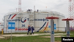 FILE - Workers walk past a storage tank at the Kaleikino oil pumping station of Transneft Kama Region near Almetyevsk, Russia, April 27, 2022. (REUTERS/Alexey Nasyrov)