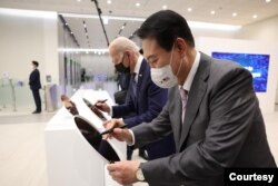 방한 중인 조 바이든(가운데) 미국 대통령이 20일 윤석열(오른쪽) 한국 대통령과 함께 평택 삼성전자 공장에서 반도체 웨이퍼에 사인하고 있다. (한국 대통령실 제공)