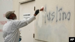 Čovek slika preko rasističkih grafita na zidu džamije u Rozvilu u Kaliforniji, 1. februar 2017. (Foto: AP/Rich Pedroncelli)