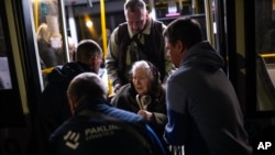 A woman who fled from the Azovstal steel plant in Mariupol is helped from a bus upon her arrival at a reception center for displaced people in Zaporizhzhia, Ukraine, May 8, 2022. 