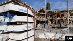 Orang-orang melihat klub kapal pesiar yang hancur akibat jatuhnya sisa-sisa drone Rusia yang ditembak jatuh di Odessa, 17 Oktober 2023, di tengah invasi Rusia di Ukraina. (Oleksandr GIMANOV / AFP)