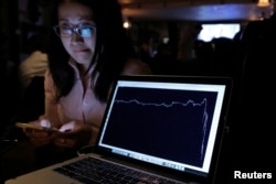 A woman watching the Brexit vote in The Churchill Tavern, a British themed pub, reacts as a graph shows the British Pound falling in value following the announcement that Britain would leave the European Union, in the Manhattan borough of New York, U.S.,