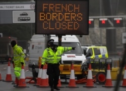 FILE - A police officer directs traffic at the entrance to the closed ferry terminal in Dover, England, Dec. 21, 2020. France banned all travel from the UK for 48 hours in an effort to stem the spread of the coronavirus disease.