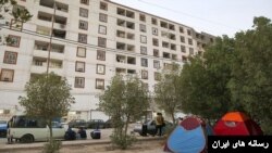 ساکنان مجتمع «عدالت ۲» از ترس خراب شدن ساختمان در گرمای ۵۰ درجه در کنار خیابان چادر زده‌اند