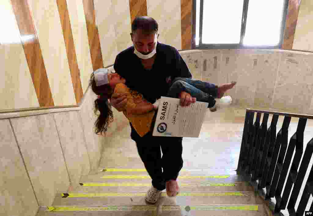 A man carries a girl that was injured during aerial bombardment at a make-shift camp for displaced Syrians, in a hospital in the Atby town of Maaret Misrin in the north of Syria's rebel-held Idlib province.