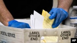 FILE - Elections workers process absentee ballots for a U.S. Senate runoff election in Atlanta, Jan. 5, 2021.