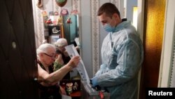 An elderly woman casts a ballot during municipal elections in Tomsk, Russia, Sept. 13, 2020.