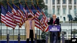 资料照片：在冲击国会大厦事件发生前举行的一次集会上，查普曼大学法学教授伊士曼(左)站在正在发言的前纽约市长朱利亚尼旁边。(2023年8月22日)