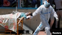 Seorang petugas kesehatan membawa seorang pasien COVID-19 di luar rumah sakit Guru Teg Bahadur, di New Delhi, India, Sabtu, 24 April 2021. (Foto: Adnan Abidi/Reuters)