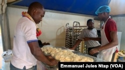 Pascal Nwal (g) dans son atelier de confection de la pâtisserie à base de la farine du manioc à Yaoundé au Cameroun le 13 janvier 2025. (Emmanuel Jules Ntap / VOA)