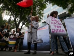 Protesters display placards while shouting slogans outside the Chinese Consulate in Manila against China's construction in a disputed are of the South China Sea, June 12, 2014.