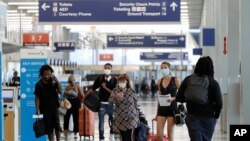 Viajeros con máscara caminan en el Aeropuerto Internacional O'Hare. Ciudadanos y residentes que viajen al extranjero podrían ser poder entrar si se considera que pueden estar contagiados, según una normativa bajo consideración.