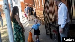 Seorang murid melambai kepada gurunya ketika dia tiba di sekolah menengah pertama St Dunstan's College ketika beberapa sekolah dibuka kembali setelah wabah COVID-19 di London, Inggris, 1 Juni 2020. (Foto: Reuters)