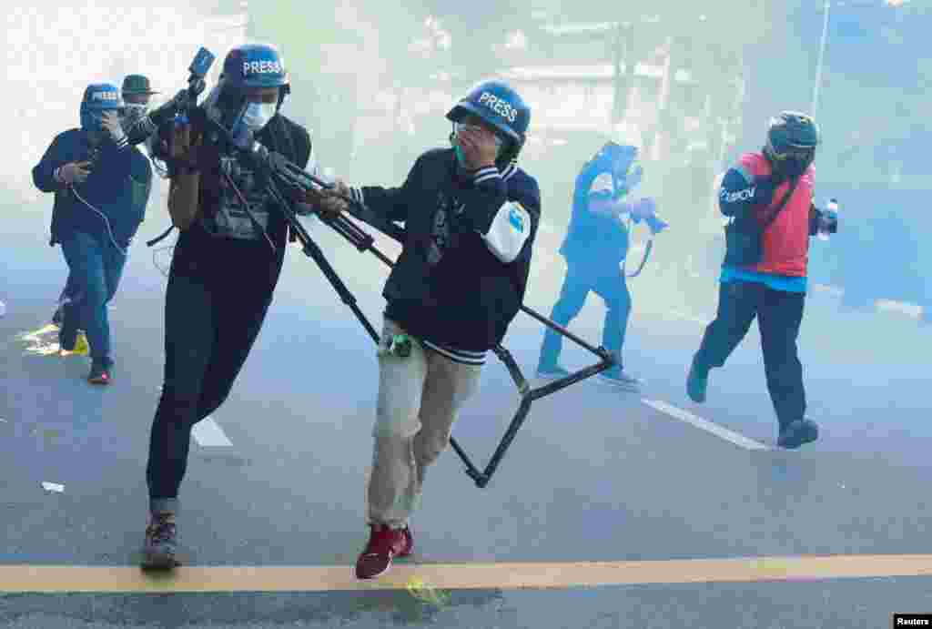 Members of the media run as they react to tear gas during a protest over the government's handling of the COVID-19 pandemic, in Bangkok, Thailand.
