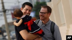 FILE - American Gordon Lake, left, and Manuel Santos Valero walk with their baby Carmen at the Central Juvenile and Family Court in Bangkok, Thailand, March 23, 2016.