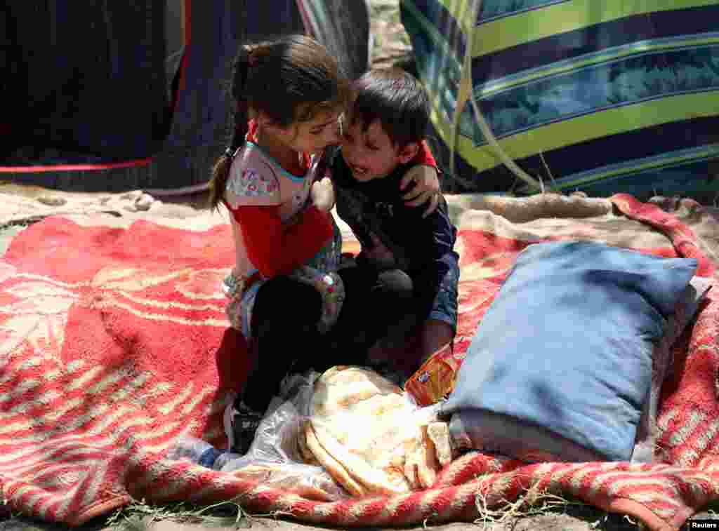 An internally displaced boy from northern provinces, who fled from his home due the fighting between Taliban and Afghan security forces, is comforted by his sister in a public park that they use as shelter in Kabul, Afghanistan.