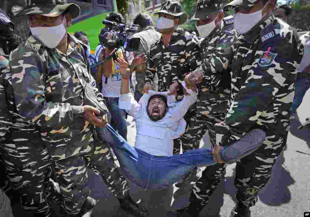Paramilitary force soldiers detain an activist protesting against Sunday's killing of four farmers in Uttar Pradesh state after being run over by a car owned by India's junior home minister, in New Delhi.