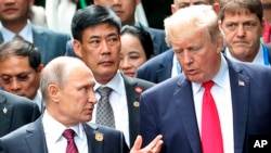 Presiden Donald Trump, kanan, dan Presiden Rusia Vladimir Putin berbincang dalam sesi foto di KTT APEC di Danang, 11 November 2017. (Mikhail Klimentyev, Sputnik, Kremlin Pool Photo via AP)