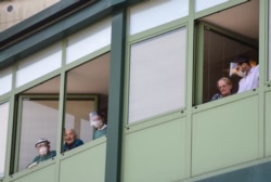 FILE - Medical personnel and hosts cheer from the windows of the Honegger nursing home where at least 35 people died from coronavirus in Albino, Italy, March 28, 2020.