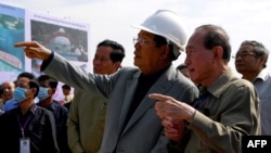 រូបឯកសារ៖ លោក​នាយករដ្ឋមន្ត្រី ហ៊ុន សែន (ពាក់មួកស) ចូលរួម​ក្នុង​ពិធី​សម្ពោធ​ការដ្ឋាន​សាងសង់​ស្ពាន​មួយ​ឆ្លង​ទៅ​ទន្លេ​បាសាក់ ភ្នំពេញ ថ្ងៃទី២៦ ខែតុលា ឆ្នាំ២០២០។ 