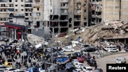 People gather as vehicles drive near damaged buildings, in Beirut's southern suburbs, after a ceasefire between Israel and Hezbollah took effect, Lebanon, Nov. 27, 2024. 
