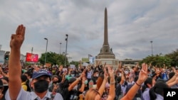 Pro-democracy activists flash three-fingered salutes during a demonstration at Victory Monument in Bangkok, Thailand, Oct. 21, 2020. Student activists applied to a Bangkok court to revoke a state of emergency the government declared last week.