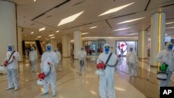 Cleaners in hazmat suits demonstrate disinfection as workers remodel a display window at Siam Paragon, an upmarket shopping mall, in Bangkok, Thailand, May 14, 2020. 