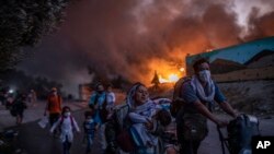 پناهجویانی که پس از آتش سوزی در کمپ "ماریو'' واقع در جزیرهٔ لسبوس در حال فرار استند (تصویر از آرشیف صدای امریکا) 