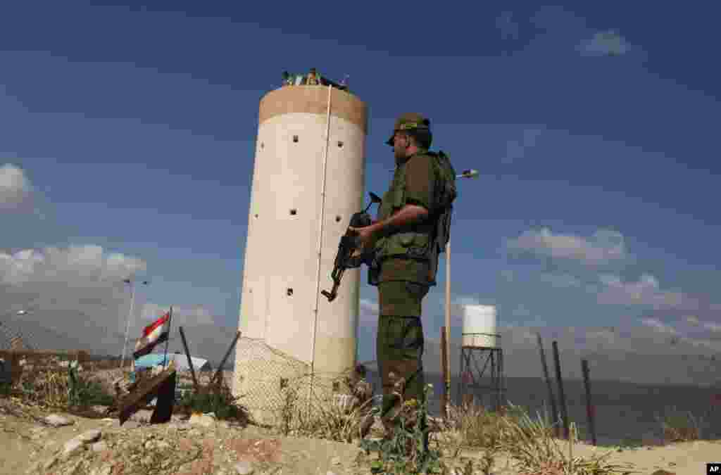 Palestinian Hamas security guard stands near an Egyptian watch tower on the border with Egypt in Rafah, southern Gaza Strip, July 5, 2013. An Egyptian official said the country's border crossing with Gaza Strip in northern Sinai has been closed indefinitely.
