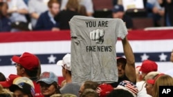 FILE - A Trump supporter holds a T-shirt reading "You Are Fake News" before a rally by President Donald Trump in Rochester, Minn., Oct. 4, 2018. Freedom House says that democracy in the U.S. weakened significantly and partly blames U.S. President Donald Trump.