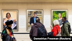 Visitors examine Betsy Ashton's exhibition, "Portraits of Immigrants" at Riverside Church in New York, U.S.