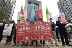 Aksi kelompok hak asasi manusia pada Hari Hak Asasi Manusia internasional PBB, untuk memboikot Olimpiade Musim Dingin Beijing 2022 di depan gedung Bank of China di Taipei, Taiwan, Jumat, 10 Desember 2021.