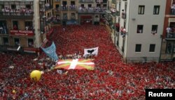 Para peserta festival dengan gembira mengangkat syal merah mereka saat akan dimulainya Festival San Fermin di Pamplona (6/7). Peluncuran roket tradisional "Chupinazo" menandai dibukanya festival yang akan berlangsung hingga 14 Juli mendatang ini.